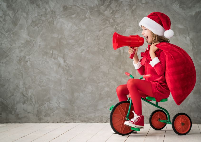 Foto di bambina con abito natalizio sul triciclo